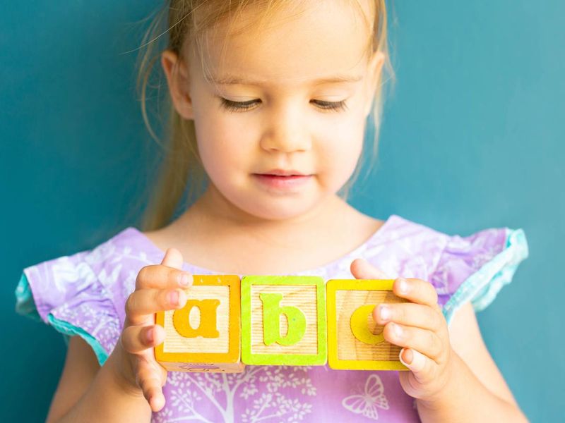 A little girl playing with alphabet blocks. Children learning abc.