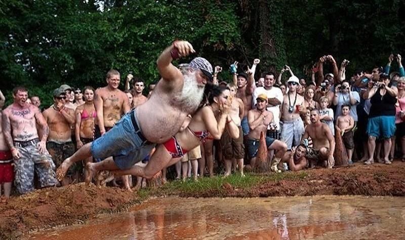A man and a woman engage in mud-pit belly flopping