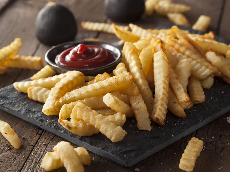 A plate of crinkle French fries and ketchup