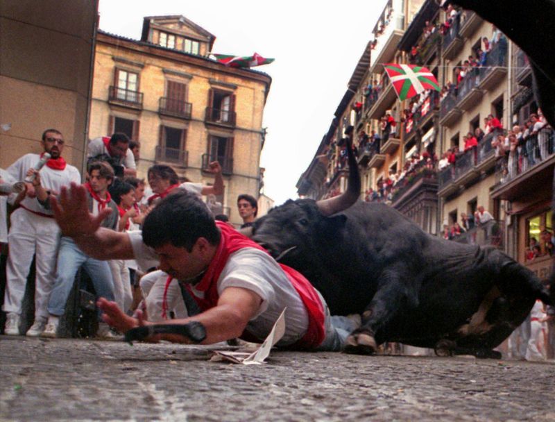 A runner falls in front of fighting bull