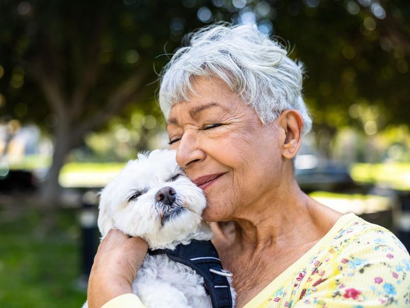 A senior woman holding her puppy outdoors