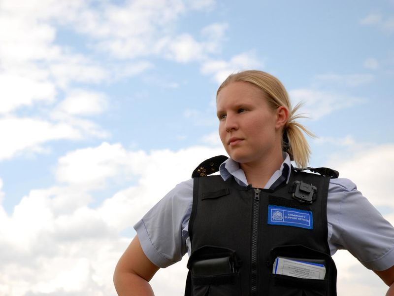 A woman in a police vest standing in front of the sky