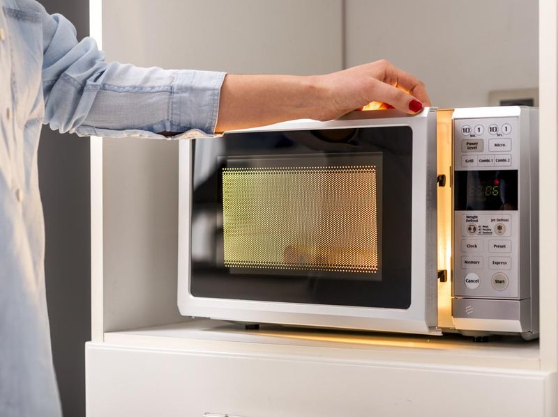 A Woman's Hands Closing Microwave Oven Door