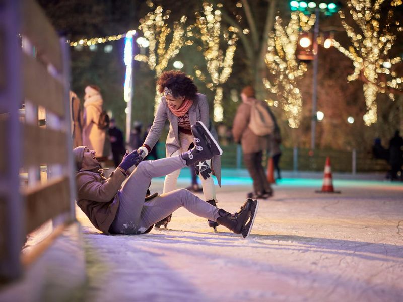 A young guy falling down at skating at ice rink. Skating, closeness, love, together