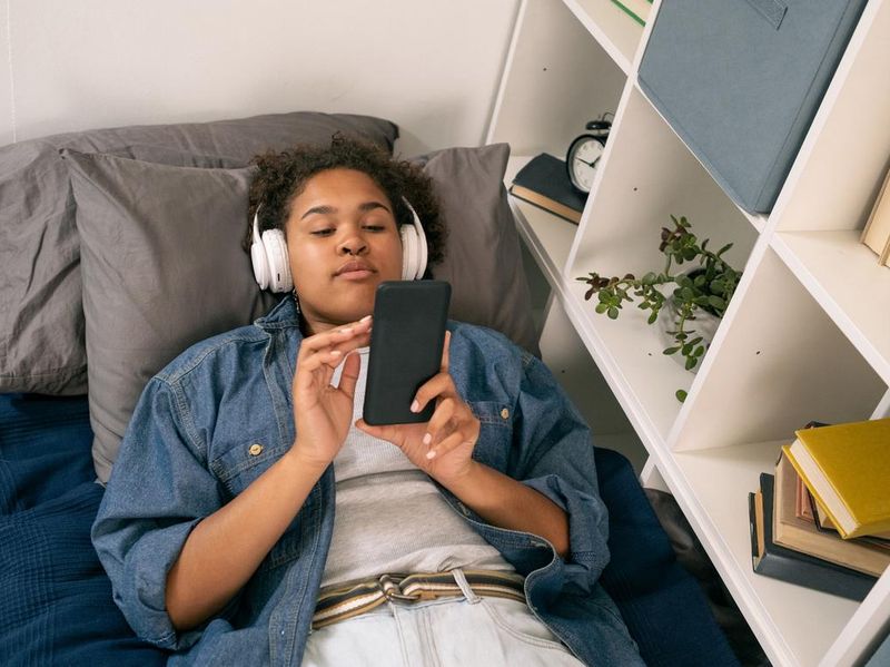 AFrican female teenager with headphones scrolling through playlist
