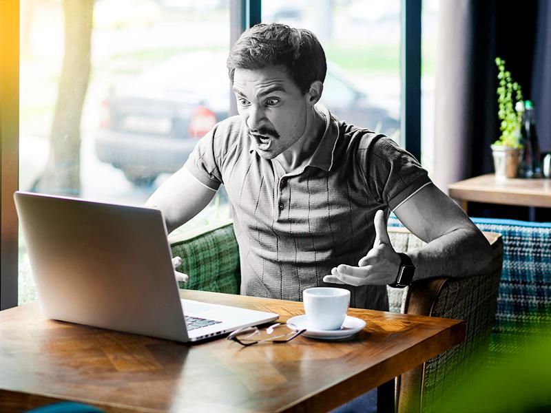 Angry man on laptop in cafe