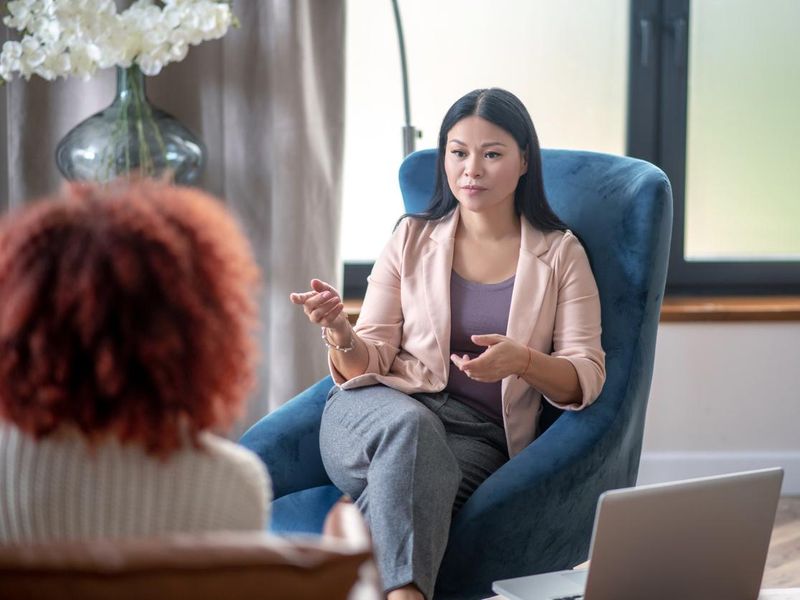 Asian professional female psychologist speaking with client