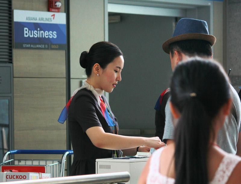 Asiana Airlines flight attendant checks in passengers for boarding
