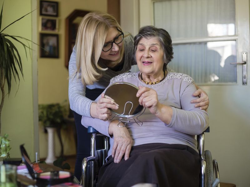 At home caregiver helping senior woman in wheelchair