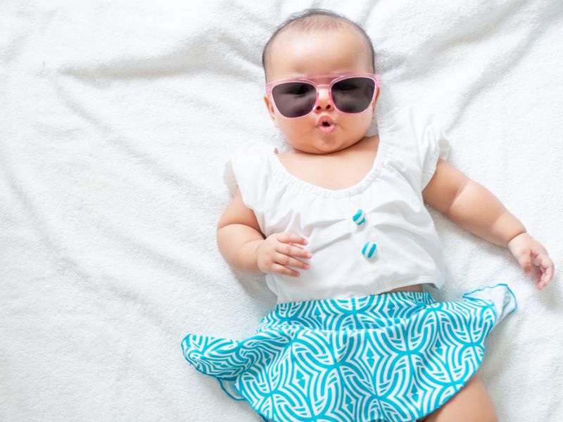 Baby girl wearing swimming suit and pink sunglasses