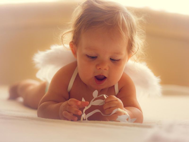 Baby girl with angel wings playing on bed