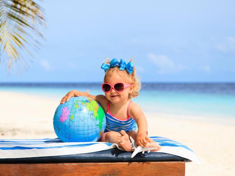 Baby holding a globe at the beach