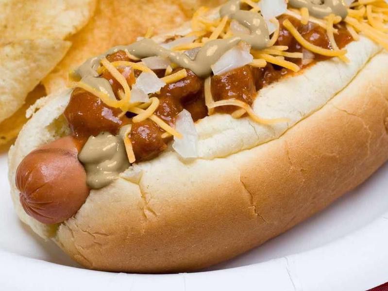 Ballpark mustard on a hot dog with chili, cheese and onions