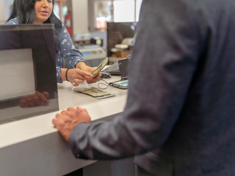 Bank teller counting money for customer