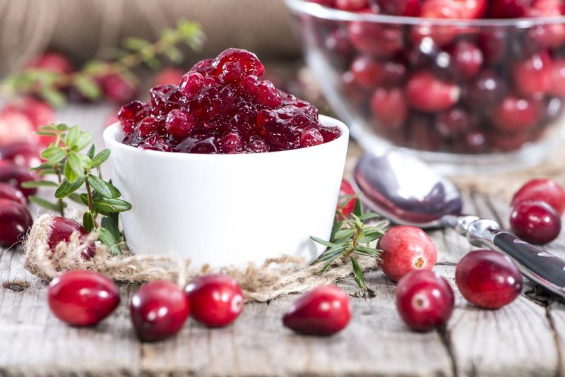 Bowl of cranberry jam, surrounded by cranberries