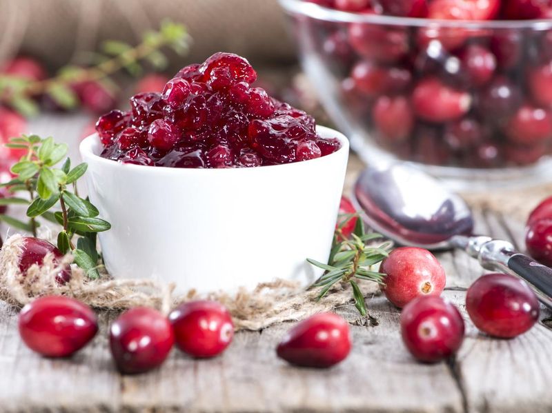 Bowl of cranberry jam, surrounded by cranberries