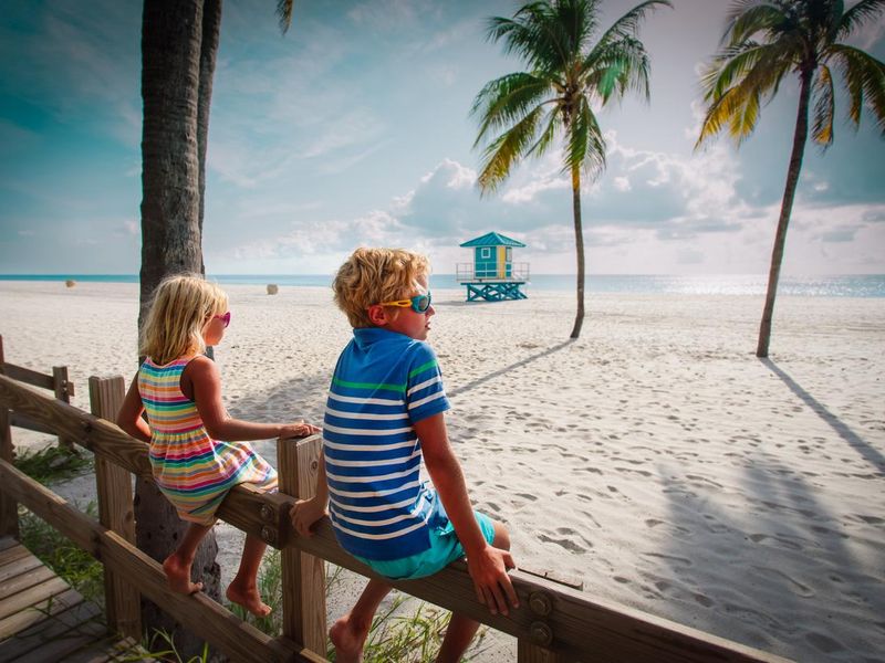 Boy and girl looking at tropical beach with palms, family on vacation in Florida