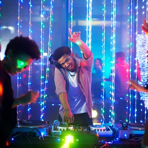 Portrait of a happy young DJ playing music at a party in a nightclub