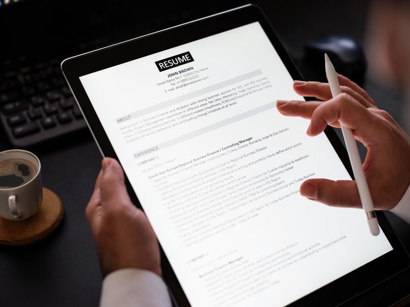 Businessman Reading A Resume On Digital Tablet To Hire Correct Personnel