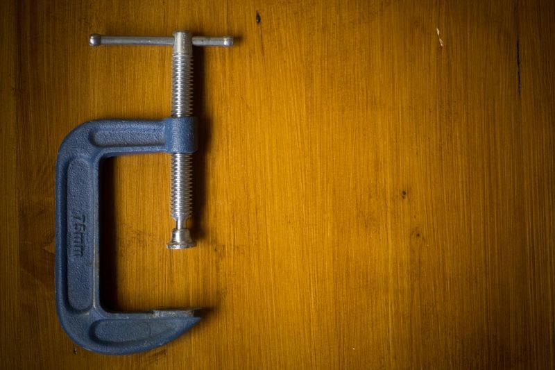 C clamp on a wooden background