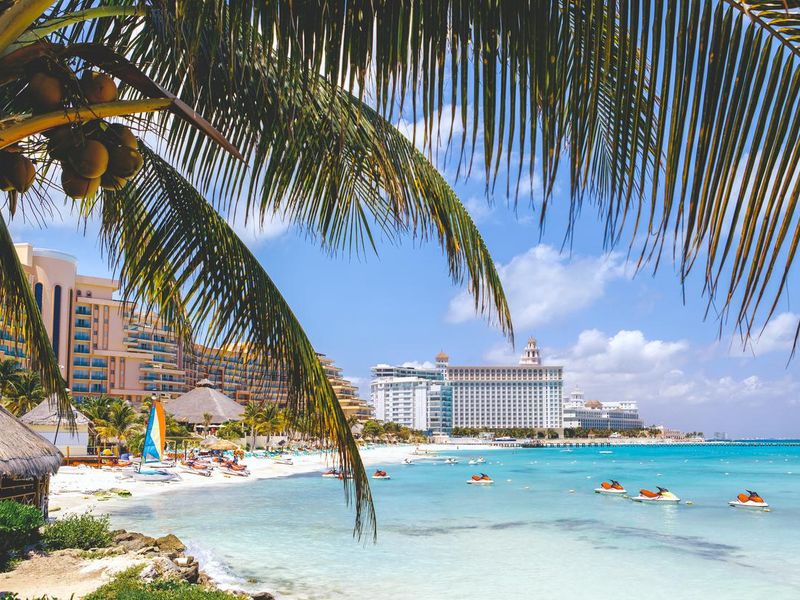 Cancun beach with hotels and plam tree in foreground