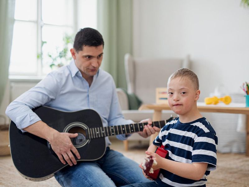 Cheerful down syndrome boy with father playing musical instruments