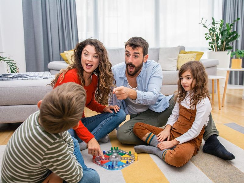Cheerful parents playing board game with their children