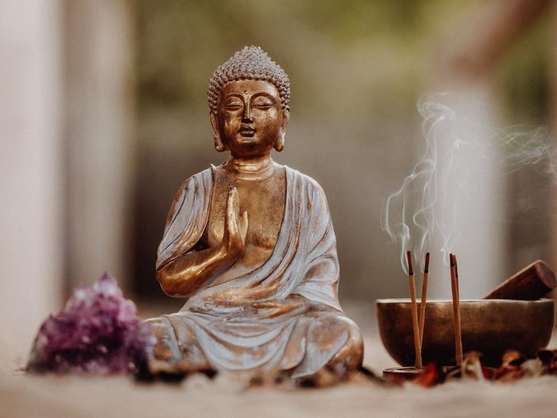 Close up of a Buddha figurine and smoky incense with gong and amethyst