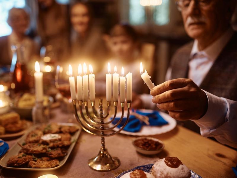 Close up of senior man lighting menorah during family dinner on Hanukkah.