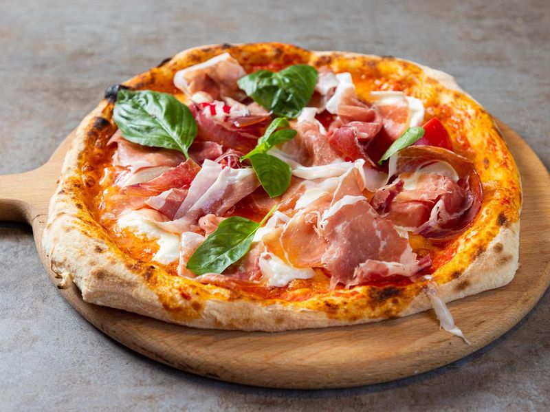 Close-up on pizza with prosciutto and basil
