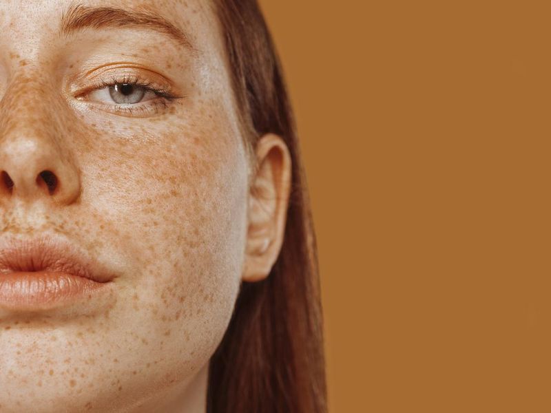 Close-up portrait of half face of a red-haired girl with freckle