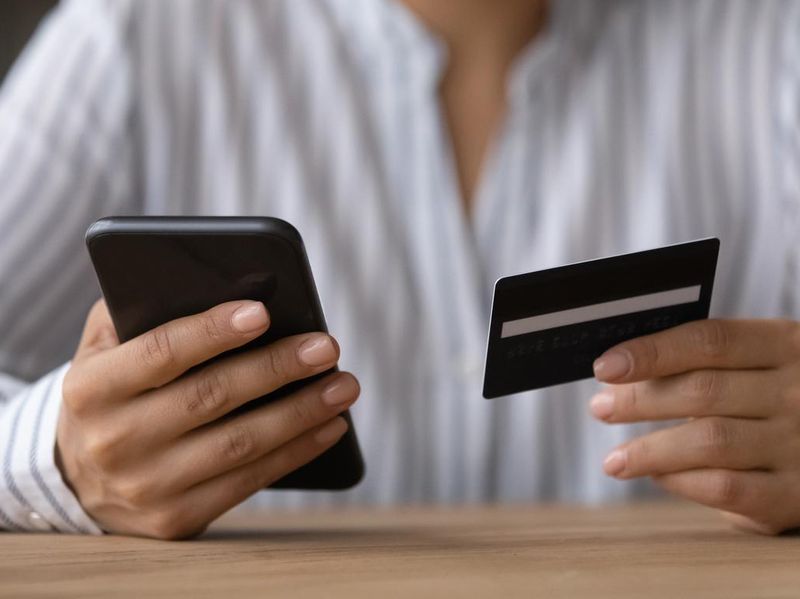 Close up woman paying online by credit card, using smartphone