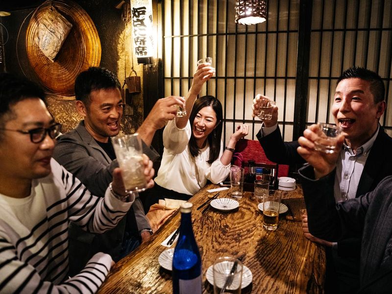 Co-workers in Japanese restaurant toasting drinks