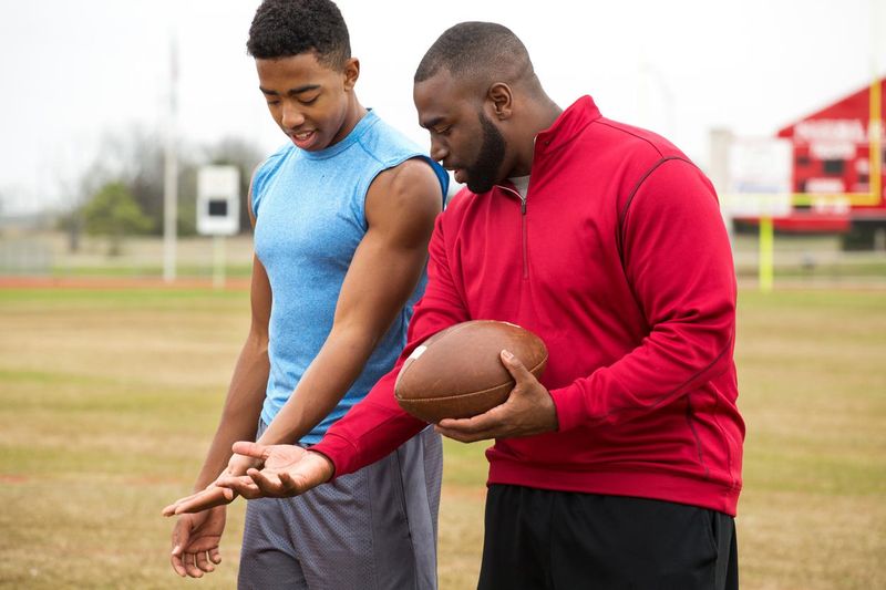 Coach training a high school athlete for football