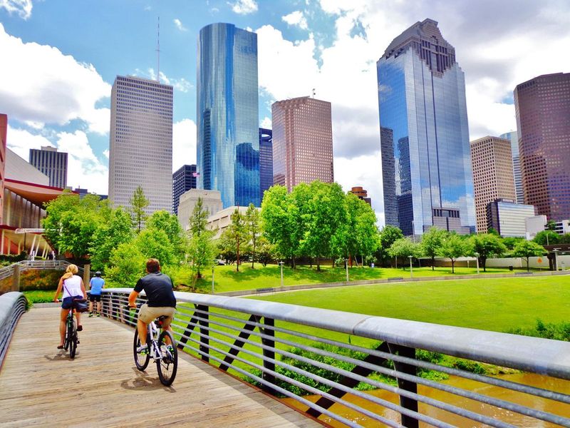 Couple Riding Bikes Across Bridge in Downtown Houston Park