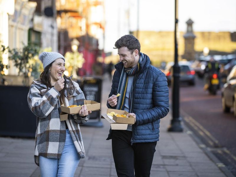 Couple sharing fish and chips and laughing