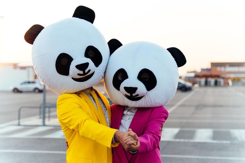 Couple wearing giant panda heads