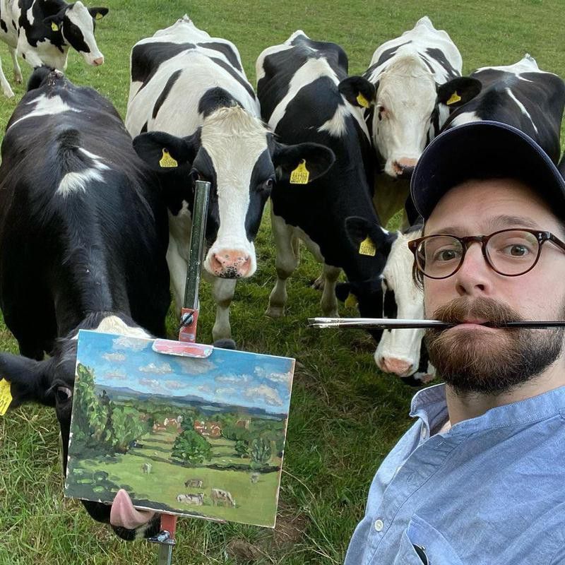 Cows photobombing man painting them