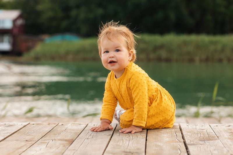 Cute smiling child sitting on a pier by the river