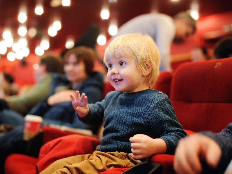 Cute toddler boy watching cartoon movie in the cinema