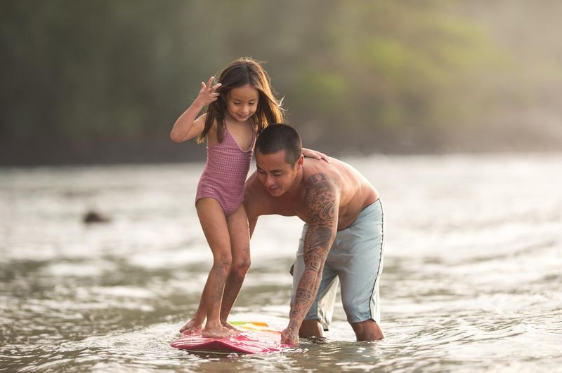 Dad teaching daughter to surf