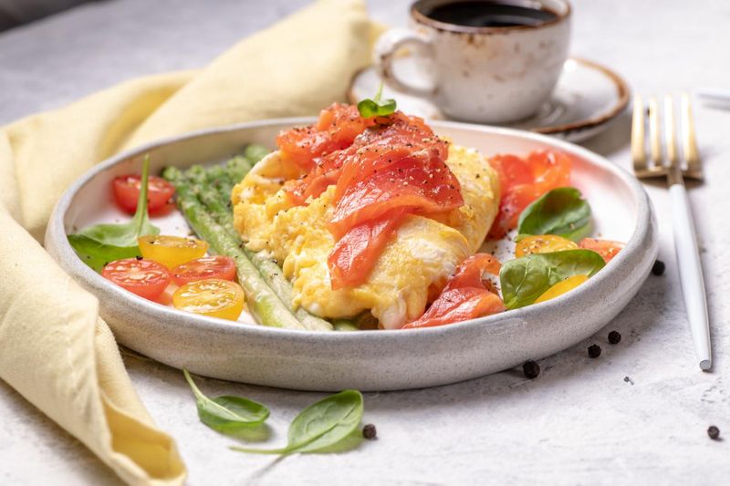 Egg omelet with green asparagus, salmon, cherry tomatoes and fresh spinach