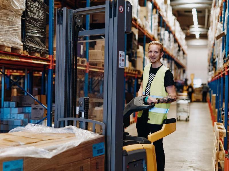 Employee in warehouse, driving forklift
