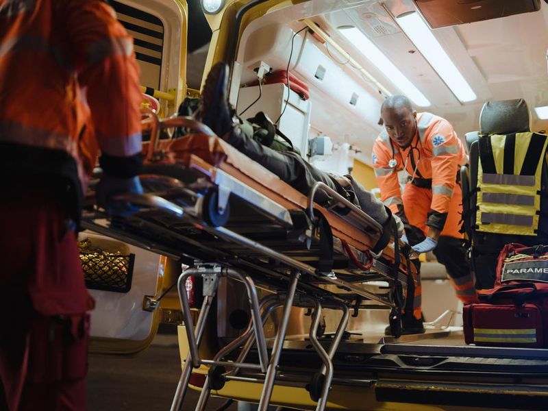 EMS paramedics lifting employee into ambulance
