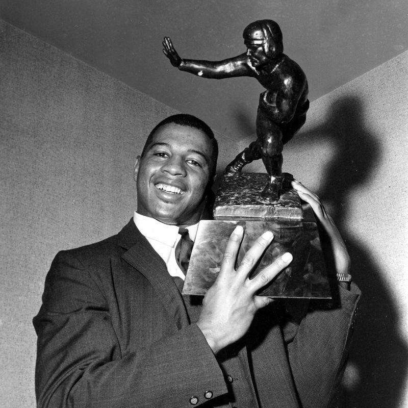 Ernie Davis holds the Heisman Trophy