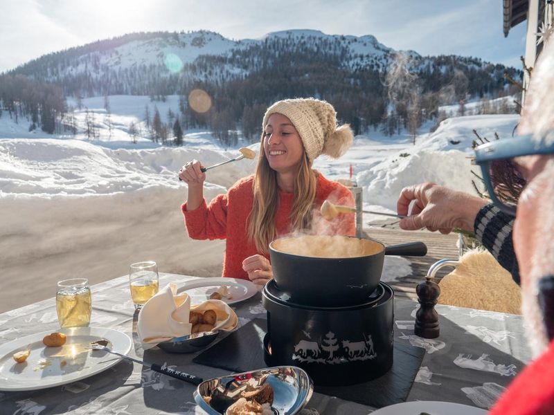 Family eating Swiss cheese fondue in the Alps in winter