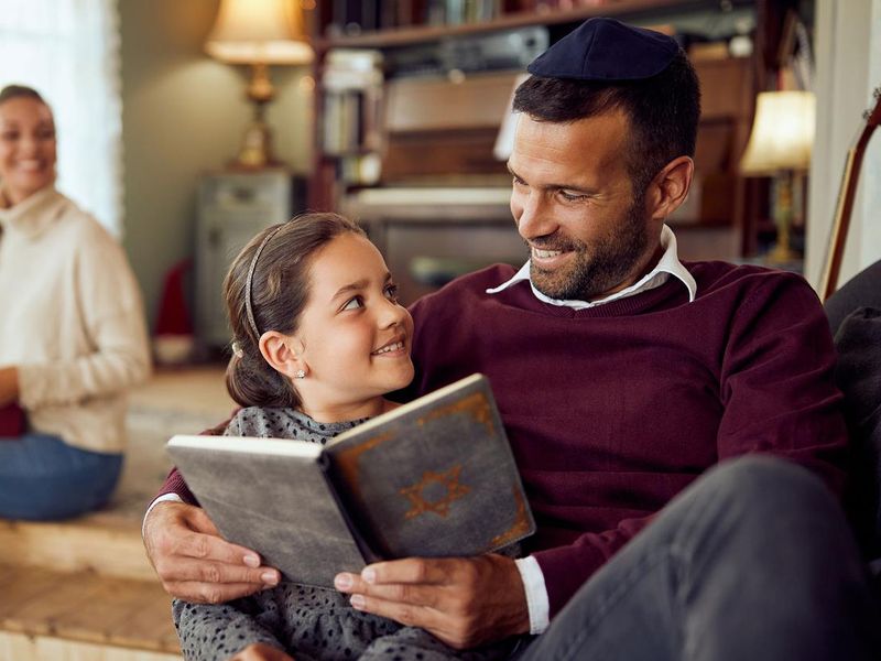 Father and daughter talking while reading Hebrew bible