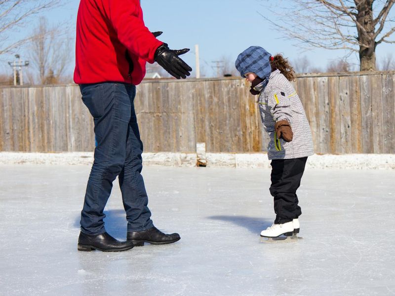 Father teaching daughter how to ice skate