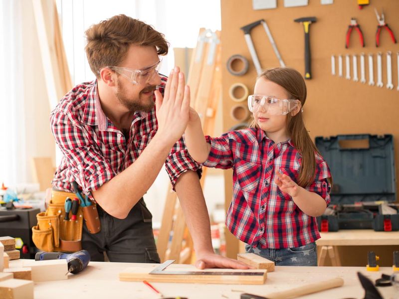 Father with his cute little daughter in woodshop.