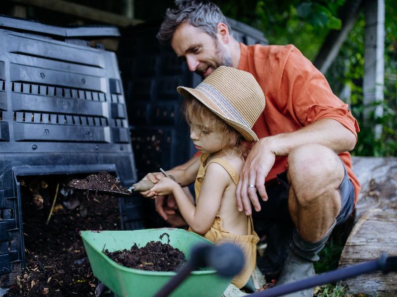 Father with his daughter putting compost